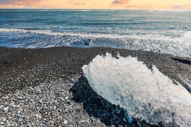İzlanda 'da gün batımında Elmas Sahili' ndeki buzdağları canlı gökyüzü ve çakıl taşlarıyla