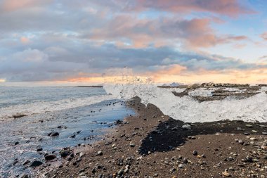 İzlanda 'daki Diamond Sahili' nde gün batımında siyah kumsalda pırıl pırıl buz parçaları