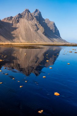Gün batımında İzlanda, Stokksnes Burnu 'ndaki Vestrahorn Dağı' nda. İnanılmaz İzlanda manzarası ve deniz manzarası. Popüler turist eğlencesi. En ünlü seyahat yerleri.