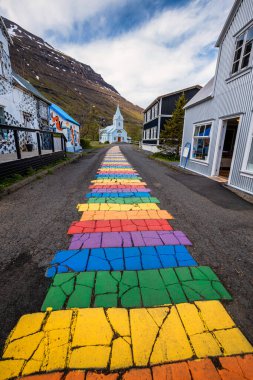 Seydisfjordur 'daki ünlü gökkuşağı yolu. Etrafında İzlanda binaları var. Sanat eserleri boyalı duvarlar. İzlanda 'nın Seydisfjordur kasabası.