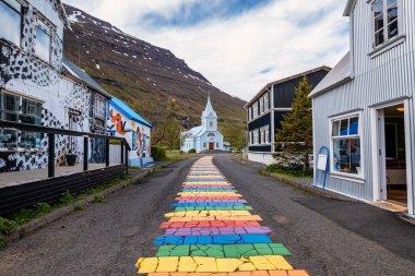 Seydisfjordur 'daki ünlü gökkuşağı yolu. Etrafında İzlanda binaları var. Sanat eserleri boyalı duvarlar. İzlanda 'nın Seydisfjordur kasabası.