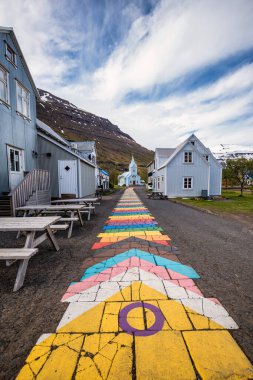 Seydisfjordur 'daki ünlü gökkuşağı yolu. Etrafında İzlanda binaları var. Sanat eserleri boyalı duvarlar. İzlanda 'nın Seydisfjordur kasabası.