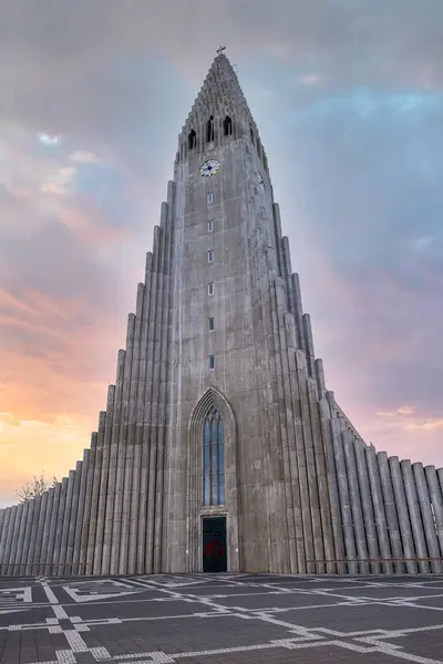 stock image Beautiful Hallgrimskirkja church and statue of explorer in center of Reykjaivk. Grass growing in front of Tallest cathedral against cloudy sky during sunset.