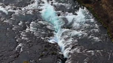 İzlanda 'daki Bruarfoss şelalesinin hava manzarası kayaların üzerinde şelale gibi akan çarpıcı mavi su İzlanda' nın el değmemiş topraklarında görülmesi gereken bir doğa harikası..