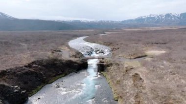 İzlanda 'daki Bruarfoss şelalesinin hava manzarası kayaların üzerinde şelale gibi akan çarpıcı mavi su İzlanda' nın el değmemiş topraklarında görülmesi gereken bir doğa harikası..