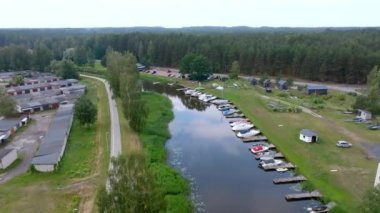 Rıhtımlı tekneleri ve komşu ormanı ve yerleşim alanı olan küçük bir marinanın havadan görüntüsü.