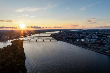 Letonya 'nın Riga şehrinin manzarasını birbirine bağlayan birden fazla köprüyle Daugava Nehri üzerinde sersemletici bir gün batımı..