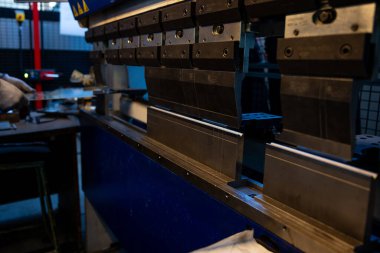 İşçi, fabrika ortamında hassasiyet odaklı endüstriyel bir basın makinesinde metal bir levha hazırlıyor..