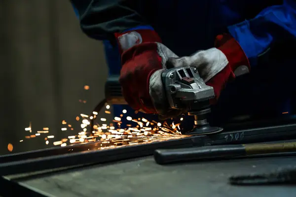 stock image Craftsman using an angle grinder, creating bright sparks while working on a metal frame in the workshop.