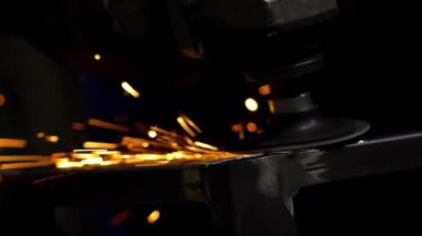 Bir öğütme aracı metal bir parça üzerinde çalışır, parlak kıvılcımlar yaratır, karanlık bir arka plana karşı, metal üretiminin hassasiyetini vurgular..