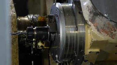 Bir metal çalışma makinesinin Milli ve Alet Tutucu 'na odaklanmış detaylı bir görüntüsü. Metal talaşları ve yağlama aktif bir endüstriyel ortam olduğunu gösteriyor..