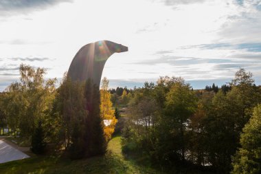 Benzersiz bir üçgen gözlem kulesi, sakin bir sonbahar kırsalında, altın ve yeşil yapraklarla çevrili küçük göller ve yoğun ormanlar üzerinde yükselir..