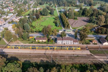 Bereketli yeşillik ve bitki yataklarının yer aldığı kentsel yapılarla çevrili sarı raylı bir botanik bahçesinin hava perspektifi..