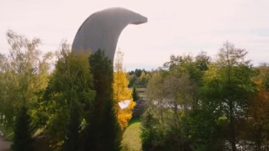 Benzersiz bir üçgen gözlem kulesi, sakin bir sonbahar kırsalında, altın ve yeşil yapraklarla çevrili küçük göller ve yoğun ormanlar üzerinde yükselir..