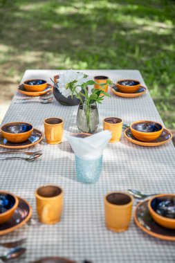 Güneşli bir yaz gününde bahçesinde güzel toprak eşyalar olan bir masa.