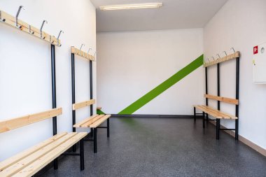 Modern Locker Room with Vibrant Green and White Striped Walls, Wooden Benches, and Coat Hooks clipart