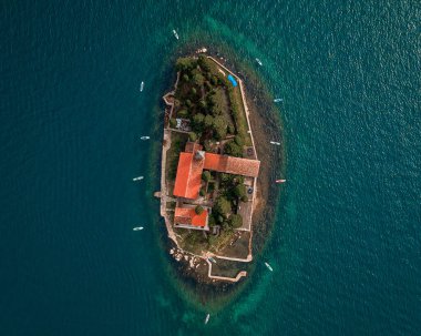 Temiz bir gökyüzünün altında turkuaz sularla çevrili tarihi bir ada kalesinin hava manzarası.