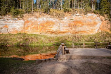 Nehir kıyısındaki ahşap izleme platformundan kırmızı kumtaşı bir uçurumun manzarası