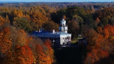 Sigulda, Letonya 'da bir kale canlı sonbahar yapraklarıyla çevrilidir. Ayrı mimari, açık bir gökyüzünün altındaki altın ve turuncu renkli ağaçlarla çelişiyor..