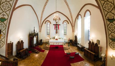 Kilisenin içinde dizayn edilmiş bir sunak, kemerli tavanlar, vitray, avize ve kırmızı halı bulunur..