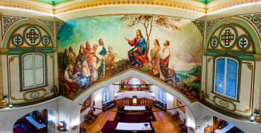 Kilisenin içinde İsa ve müritlerinin canlı bir duvar resmi, dekoratif mimari, vitray pencereler ve merkezi bir sunak bulunur..