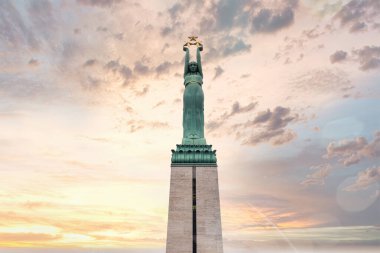 Riga, Letonya 'daki Özgürlük Anıtı, Pastel renkli bulutlarla dolu bir gökyüzünde üç yıldız tutan bir kadın figürüyle ayakta duruyor..
