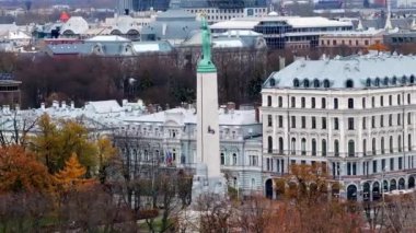 Özgürlük Anıtı Letonya 'nın Riga kentindeki tarihi binaların arasında duruyor. Sonbahar ağaçları, klasik ve modern mimarinin bir karışımı ile canlı renkler ekler ekler..