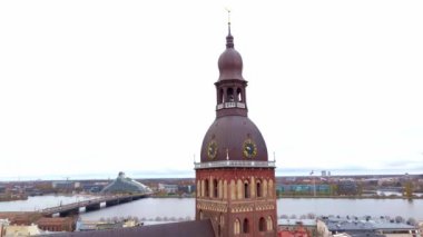Riga Katedrali 'nin saat kulesi arka planda Daugava Nehri ve Letonya Ulusal Kütüphanesi ile birlikte Riga' nın mimari çeşitliliğini gözler önüne seriyor..