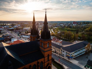 Gün batımında küçük bir kasabada iki sivri kulesi olan tuğla bir kilise duruyor. Sahnede konut ve ticari binalar, yollar ve yeşil alanlar yer alıyor..