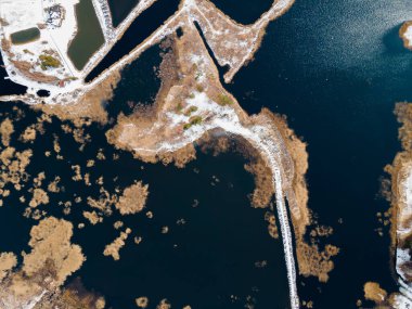 An aerial perspective reveals a network of ponds and channels, bordered by white deposits. Man made structures appear in the upper left corner. clipart