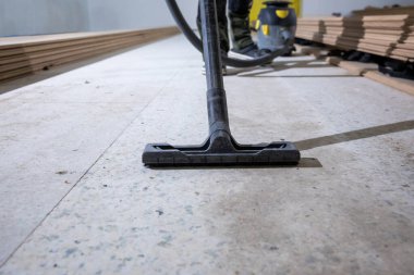 Elektrikli süpürge ahşap döşeme için zemini temizler. Arka planda ahşap kalaslar var..