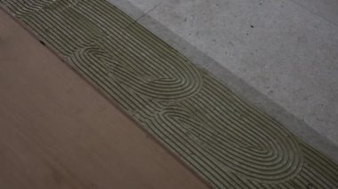 Yapışkan uygulamanın beton zemin üzerinde girdap şeklinde detaylı görüntüsü, ahşap döşeme tahtalarını içeriden hizalamada hassasiyet..