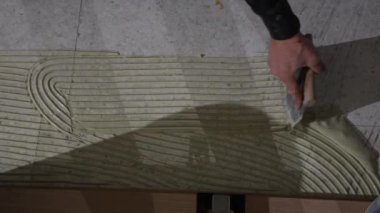 Beton zemin üzerindeki girdap desenine uygulanan yapışkan görüntüsü, döşeme kurulumunda hassasiyet ve işçiliği vurguluyor.