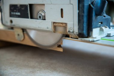 Dairesel testere bıçağı ahşabı keser ve talaş üretir. Odaklanma aracı ve zanaatkarlık, bulanık bir arka plan eylemi vurguluyor.