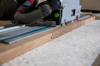 Görünür tahıl ve toz çıkarma hortumu ile dairesel testere etkin bir şekilde ahşap kesiyor, kapalı bir atölyede hassasiyet ve işçiliği vurguluyor.