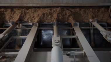 Metal kirişleri ve hidrolik bileşenleri olan ağır iş makineleri, loş ışıklandırılmış endüstriyel ortamda fibröz malzemeler, muhtemelen ahşap parçaları işlerler..