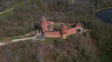 Ortaçağ kırmızı tuğlalı kalesi, silindirik ve çoklu kuleleri, güçlendirilmiş duvarları ve yolları kısmen ormanlık alana kurulmuş..