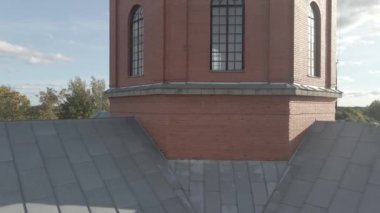 Kırsal bir köyde üzerinde haç bulunan gümüş bir kubbe. Etrafı dağınık binalar ve ağaçlarla çevrili. Arka planda parçalı bulutlu bir gökyüzü var..