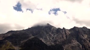 Gürcistan 'ın Kafkasya Dağları' ndaki engebeli dağ zirveleri alçak bulutlar ve güneş ışığıyla kayalık araziyi ve seyrek bitki örtüsünü aydınlatıyor..
