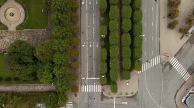 Riga, Letonya 'da bir maratonun havadan perspektifi, geniş bir yolda koşucuların, simetrik ağaçların, dairesel bir çeşmenin ve görünür kavşakların yer aldığı.