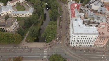 Katılımcılar Letonya 'nın Riga kentinde kanal, park ve tarihi binalarla çevrili bir cadde boyunca koşuyorlar. Tramvay rayları ve izleyiciler şehir atmosferine ekleniyor.