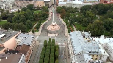 Riga, Letonya 'daki Özgürlük Anıtı' nın havadan görünüşü bir park, patikalar ve tarihi binalarla çevrili ve insanlar bir maratona katılıyorlar..