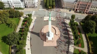 Riga, Letonya 'daki Özgürlük Anıtı' nın hava görüntüsü, yeşil alanlar, patikalar ve bir maraton etkinliğine katılan bir kalabalıkla çevrili..
