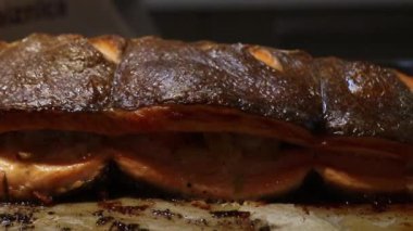 Porsiyonlara dilimlenmiş pişmiş somon balığı. Çıtır çıtır derinin üzerine serpiştiriliyor. Yumuşak turuncu iç kısımlar mutfak ortamında görülebilir..