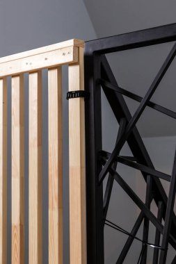 Yumuşak ışıklandırma altında siyah plastik bir mandalla korunan, açısal dizaynlı, siyah metal çerçeveli ahşap bir yapının ayrıntılı görüntüsü..