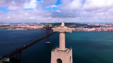 Cristo Rei heykeli Portekiz, Almada 'da kollarını açmış duruyor. 25 de Abril Köprüsü, Lizbon 'un kentsel manzarasıyla Tagus Nehri boyunca uzanır..