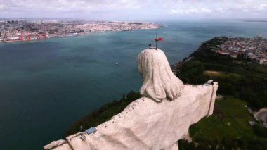 Portekiz 'in Almada kentindeki Cristo Rei heykeli, 25 Abril Köprüsü ve arka planda kentsel manzarayla Tagus Nehri' nin karşısındaki Lizbon 'a bakıyor..