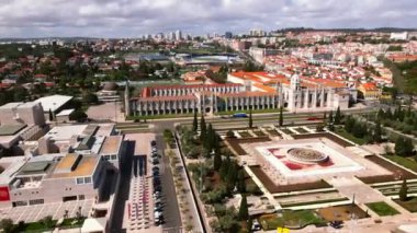 Portekiz 'in Lizbon kentindeki Jeronimos Manastırı' nda, kentin kırmızı kiremitli çatıları ve modern ufuk çizgisine karşı kurulu ayrıntılı bir cephe ve büyük bir avlu çeşmesi yer alıyor..