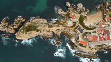 Hava görüntüsü, Portekiz 'in dramatik uçurumları ve kayalık çıkıntıları olan Penishe' yi, Atlantik Okyanusu 'nun engebeli dalgaları yakınlarındaki kırmızı çatılı binaları gösteriyor..