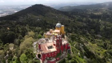 Pena Sarayı 'nın kırmızı ve sarı kuleleri Portekiz' in Sintra kentindeki yemyeşil tepelerin üzerinde yükseliyor. Romantizm mimarisi ve geniş bir çevre manzarası sergiliyor..